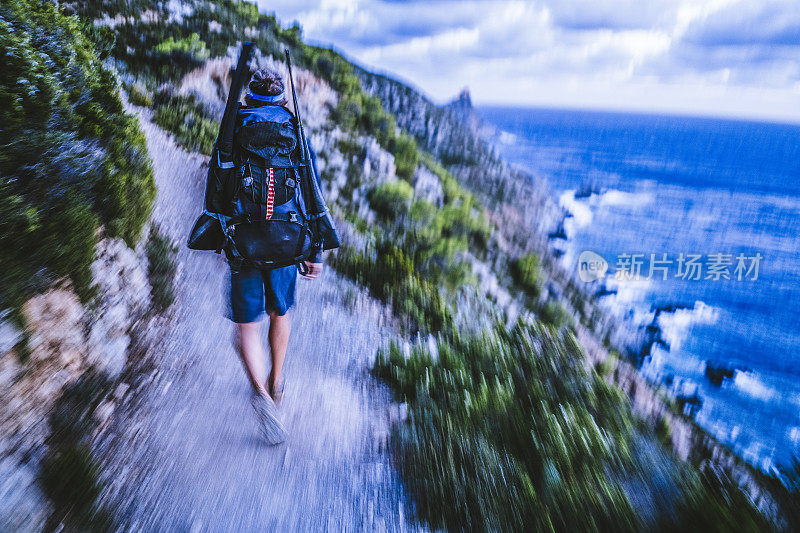 黄昏时分，潜水员沿着多岩石的海岸线散步