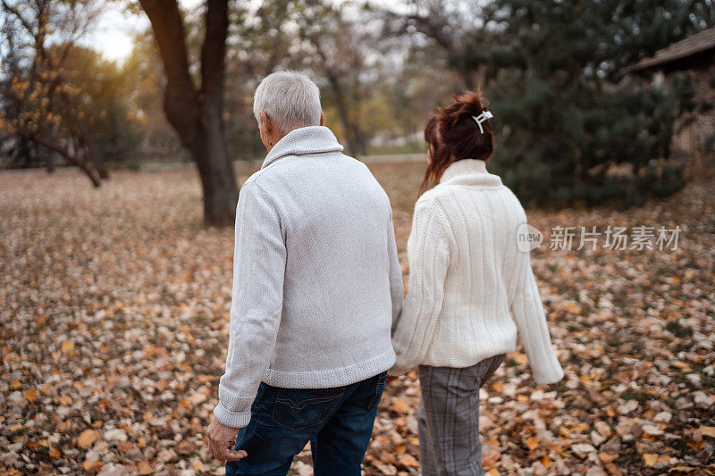 活跃的老年人在秋季公园散步