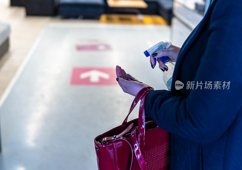 一名年轻女子在百货公司门口用酒精凝胶消毒手