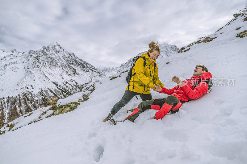 一对年轻的徒步旅行者在白雪皑皑的山脊上嬉戏