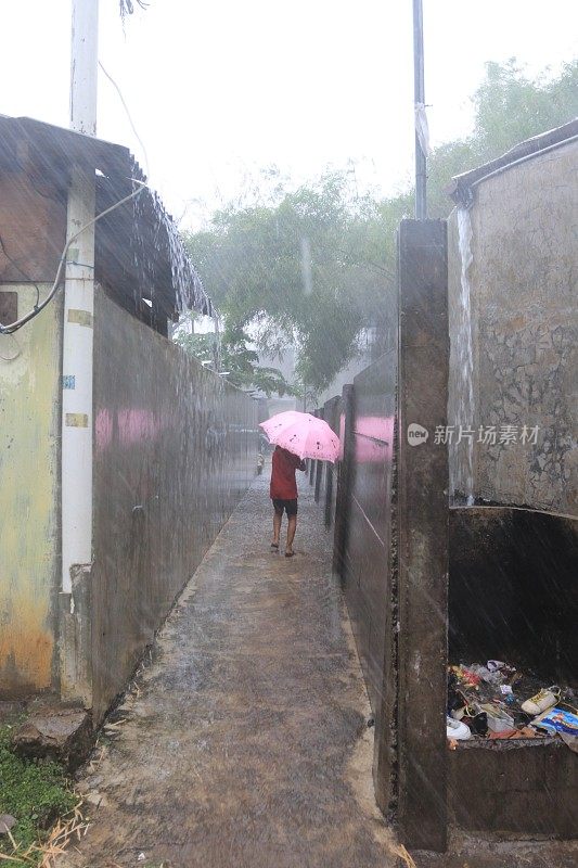 一个小女孩在倾盆大雨中带着雨伞。