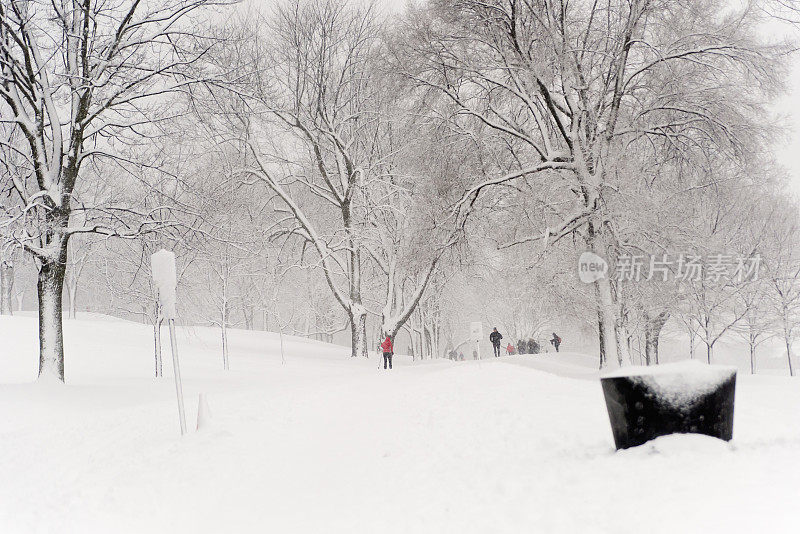 城市公园景观与不明身份的人在暴风雪。