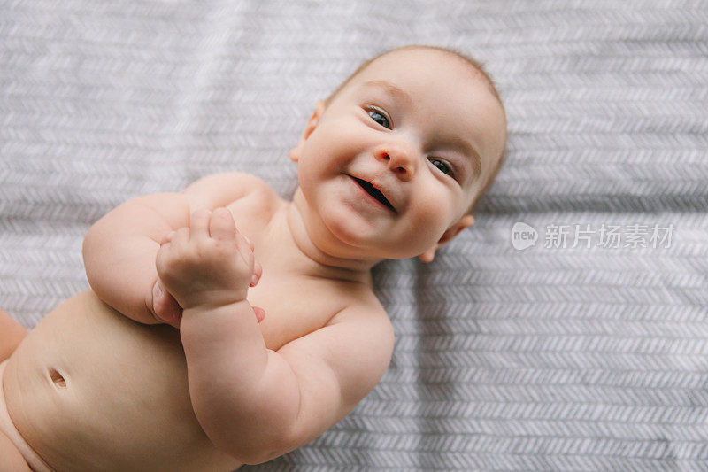 三个月大的新生儿微笑着撒谎。精神运动发展和婴儿护理