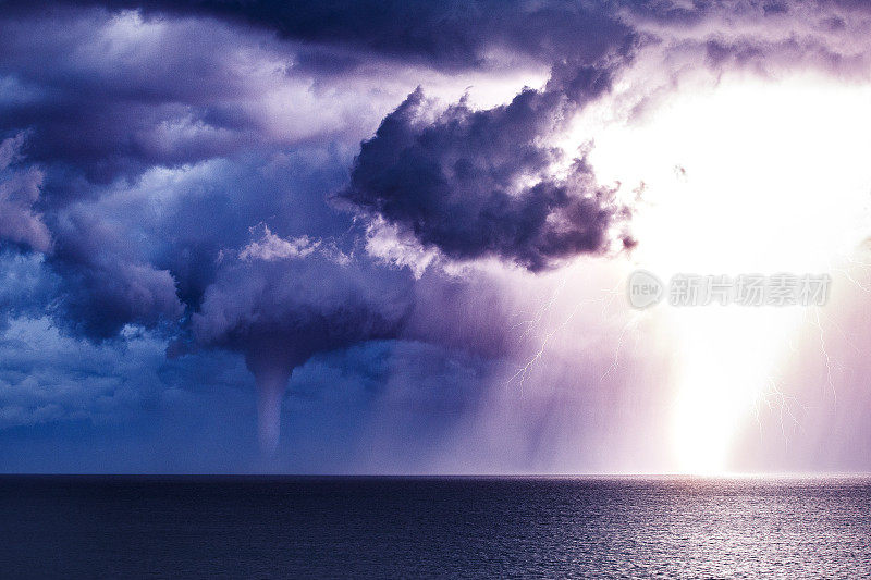 明亮的闪电与风暴单体和龙卷风水柱一起击中海洋