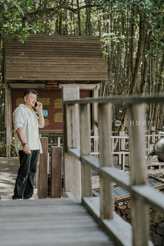 一位活跃的老人正在用手机给在自然公园度假的儿子一些建议