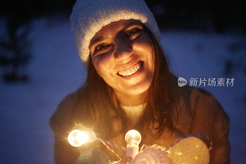 圣诞彩灯女孩看着相机在雪