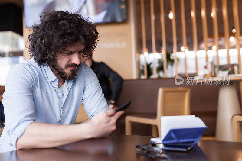在现代咖啡馆里看手机的男人。