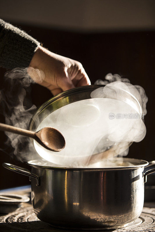 在家用炉子做饭时，一个男人打开了锅盖