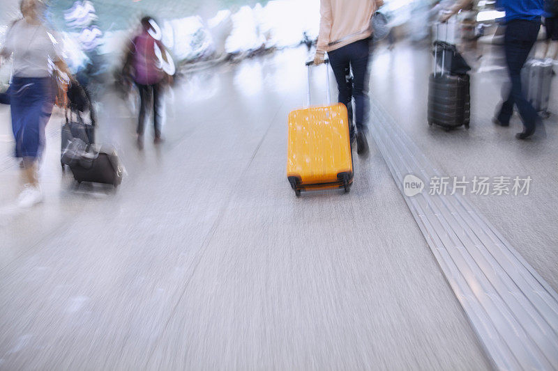 旅客在机场候机楼拿着滚动的行李急着要登机