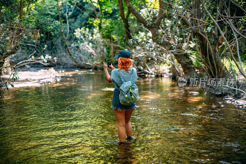 徒步旅行的女人探索河流和拍照