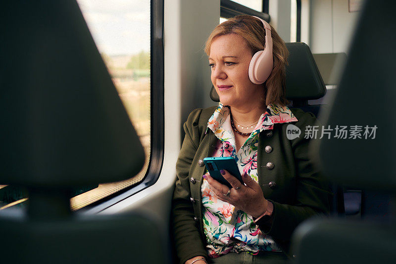 一个中年妇女，带着手机和耳机在火车上