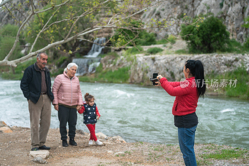 中年妇女在户外拍摄老年男子、老年妇女和孙子的照片