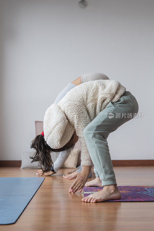 母亲和女儿在家里做瑜伽，享受一个非常私人的时刻，使他们更亲密