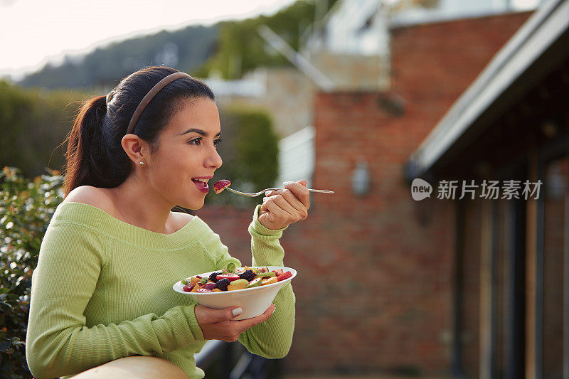 素食主题。一个西班牙可爱的年轻女人在户外午餐吃水果沙拉的特写