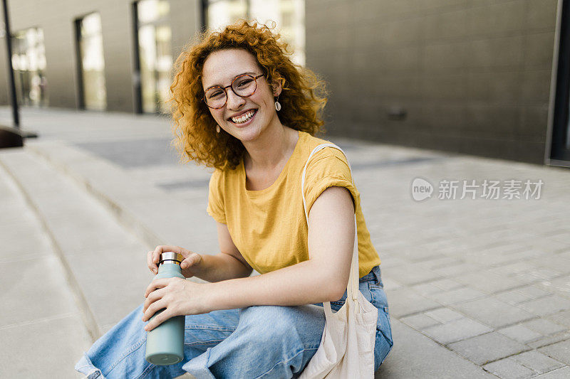 红发妇女用可重复使用的水瓶喝水，用可重复使用的棉生态生产袋购物。零废物生活方式概念