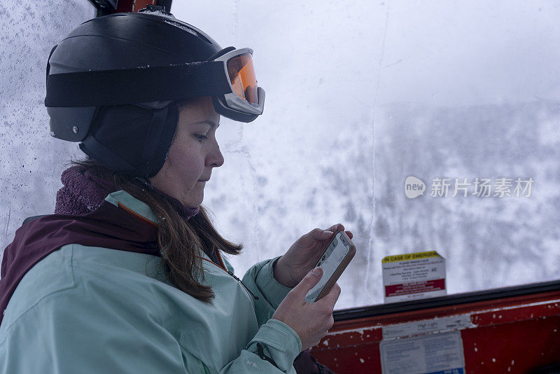 女子在滑雪缆车内用手机聊天