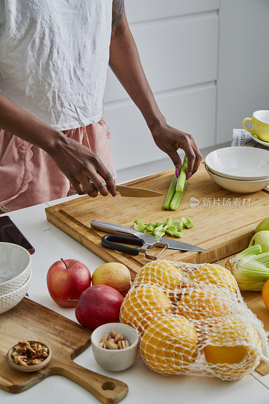 一名黑人妇女正在切芹菜根，准备健康食品