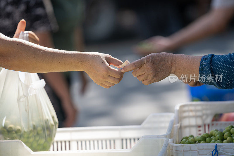 在农贸市场，人们的手互相赠送和索取土耳其里拉的特写照片