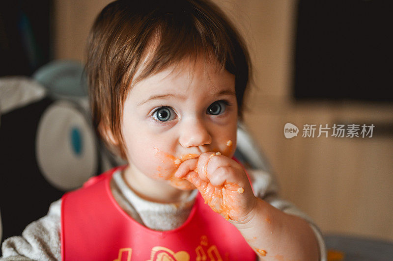 孩子在家里的高椅子上用手吃饭。