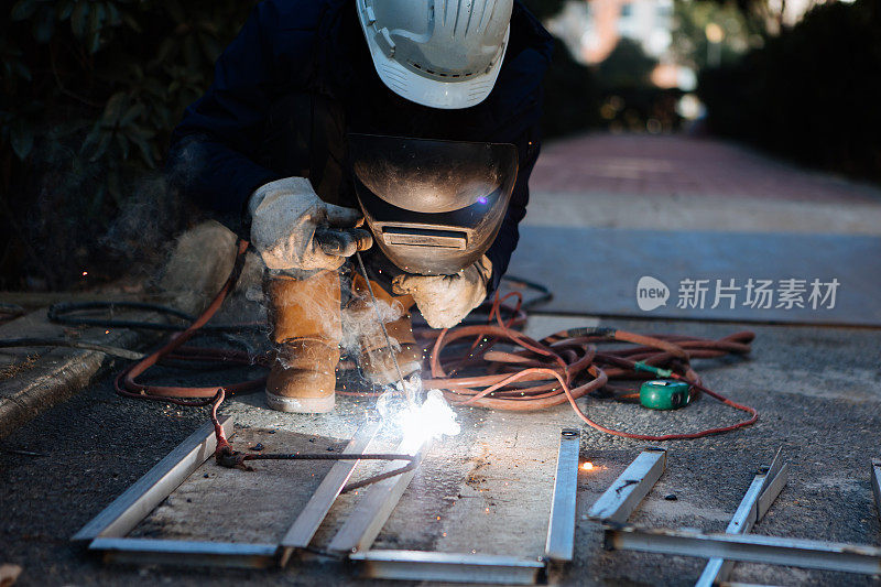 一名中年男性工人正在使用切割机和焊机