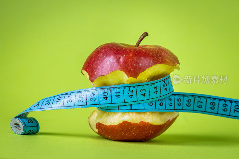减肥理念，咬苹果相关的裁缝仪表，积极的绿色背景，健康美味，积极的饮食方式
