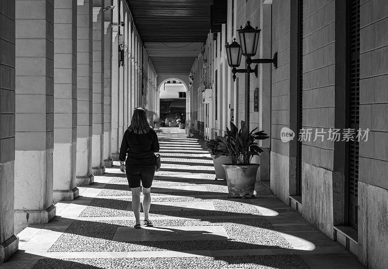 后视图妇女走在拱廊在城市