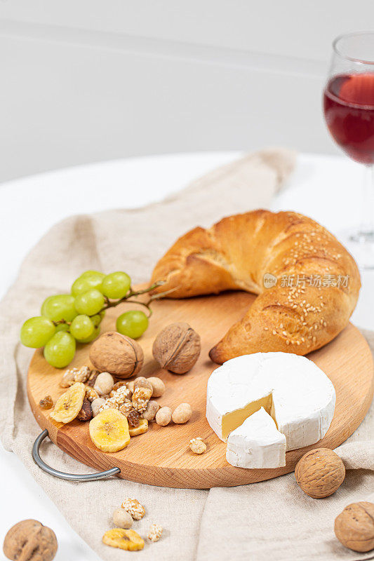 什锦奶酪，坚果，水果，羊角面包和葡萄酒。现代厨房里的奶酪拼盘