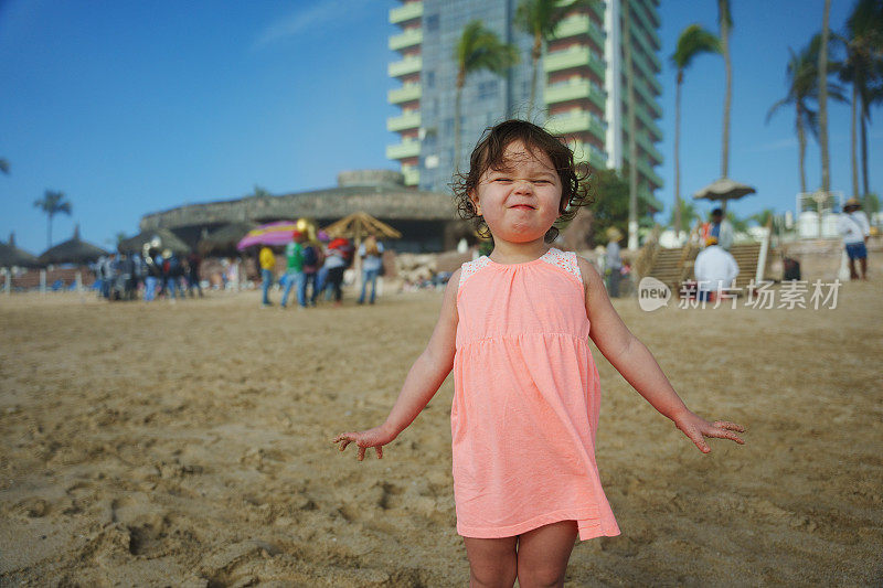 一个年轻的女孩站在沙滩上做着鬼脸