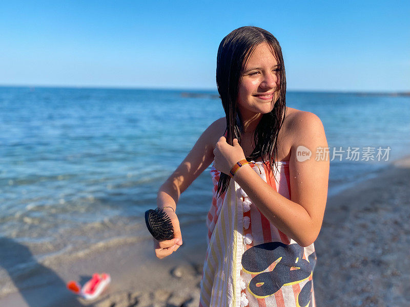 微笑的少女在沙滩上梳头