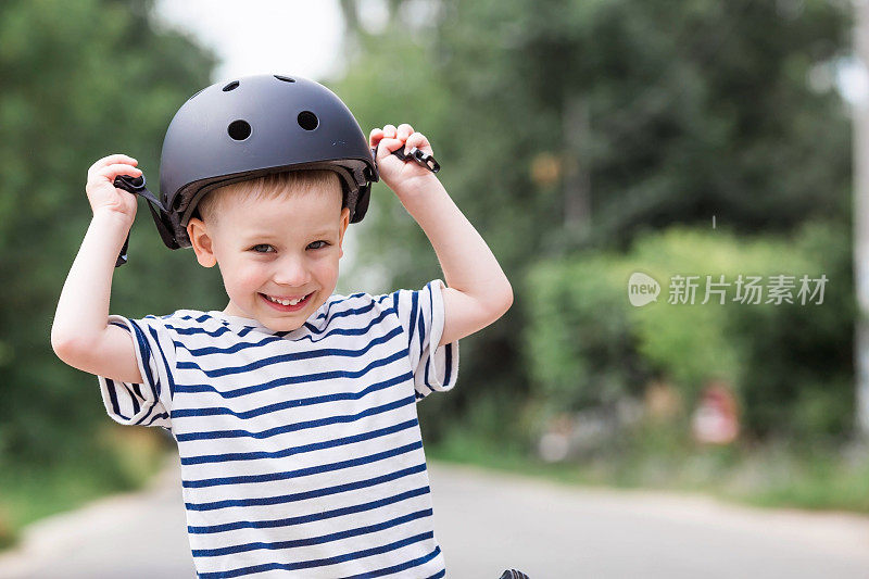 一个快乐的小男孩戴着头盔在户外骑着跑步自行车。一个快乐的孩子正在从事一项积极的运动。保护。人寿保险和儿童安全。