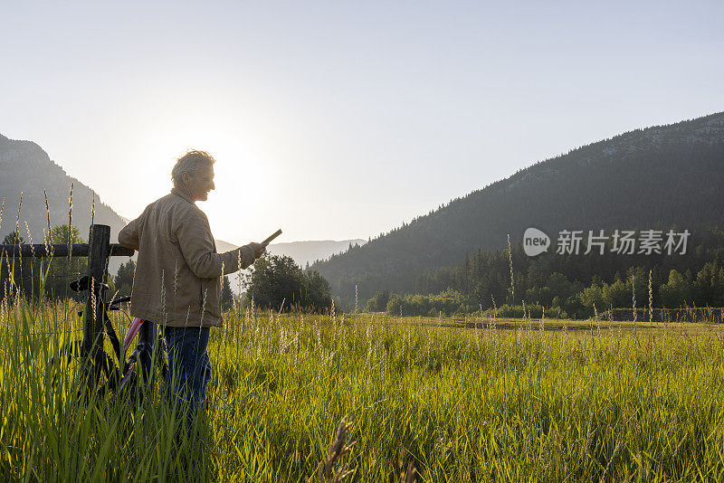 牧场主在木栅栏旁休息时使用数字平板电脑