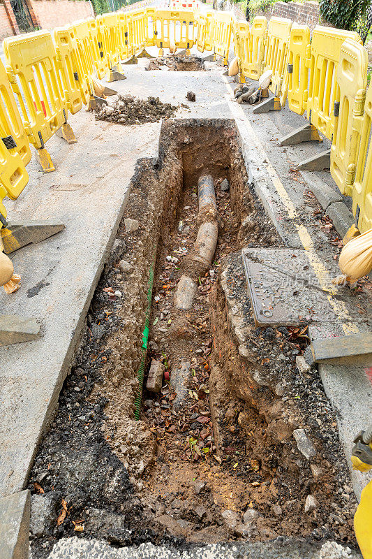 英国的道路工程正在挖掘当地的柏油路面，以修复地下的公用管道，并设置安全屏障和标志