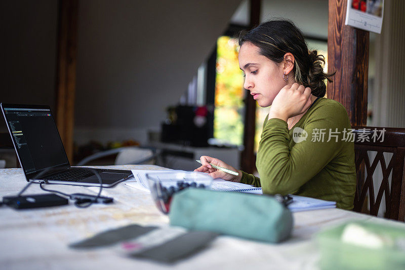 年轻女子用笔记本电脑在桌子上学习