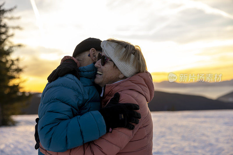 喜气洋洋的老年夫妇在雪山上互相拥抱