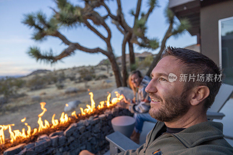 自然的和谐:一个年轻人在户外放松，沉浸在噼啪作响的壁炉的温暖中，沉思着周围风景的宁静