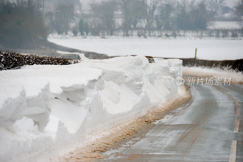 在什罗普郡的乡村公路边上堆积着大量的积雪。大雪和暴风雪过后，铲雪机为运输打开道路而堆起的积雪。