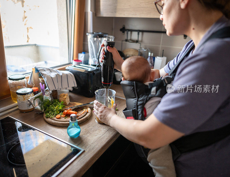 母亲用搅拌器给婴儿准备食物