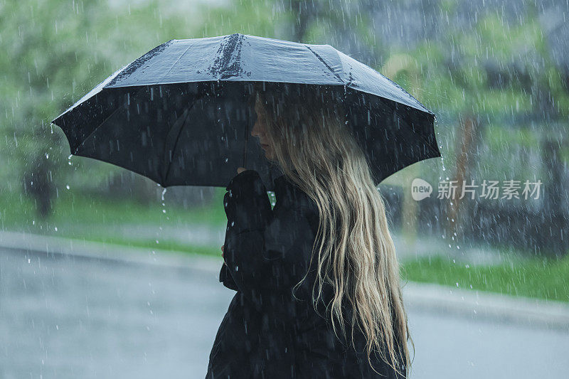 伞下的金发女人。暴风雨天气。暴雨