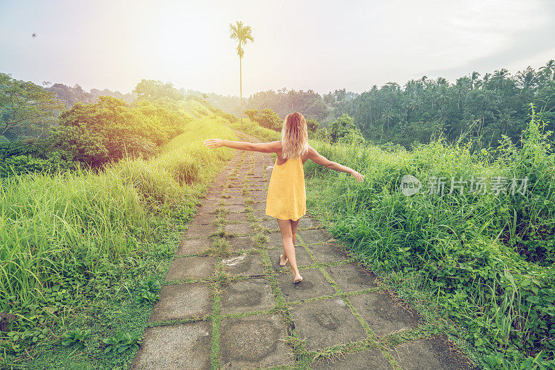 年轻女子伸开双臂在米自然中行走，乌布-巴厘岛-人们旅游热带目的地的概念