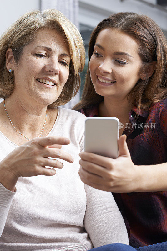 十几岁的女儿向母亲展示如何使用手机