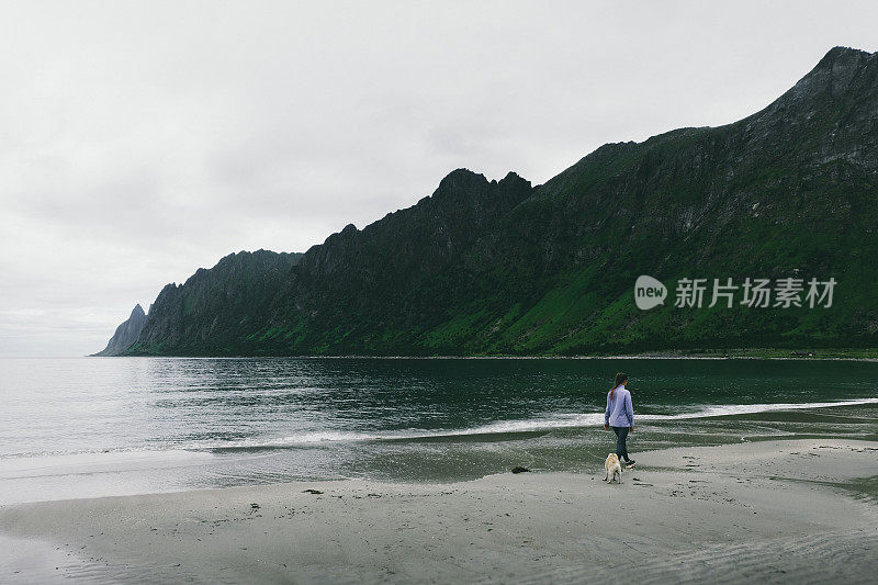 一个女人在挪威的海滩上遛狗