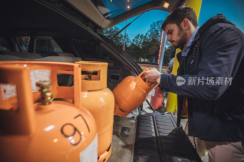 一个年轻人在加油站拿着液化石油气瓶子