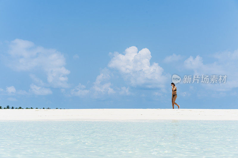 4月，年轻美丽的女子走在马尔代夫小岛海滩的水边