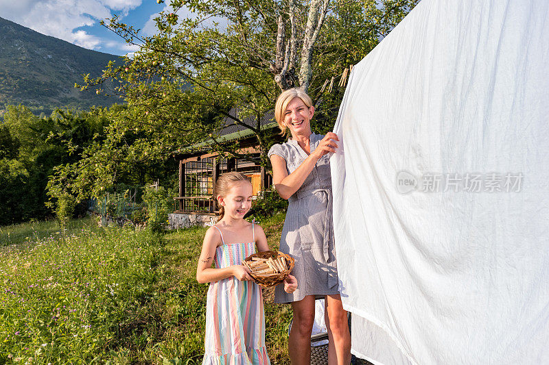 夏日阳光明媚的母亲和女儿在山野上晾衣服