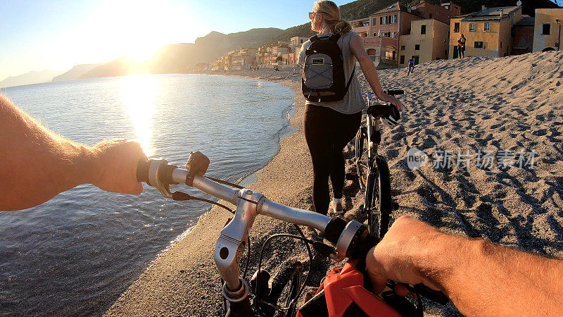 日落时分，女自行车手沿着海岸推着自行车