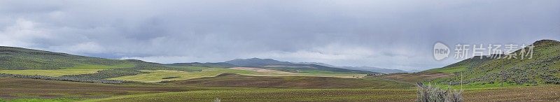 风景风暴全景从犹他州和爱达荷州的边界84号州际公路，I-84，在落基山脉与绵羊和奶牛放牧的农村农场的观点。美国。