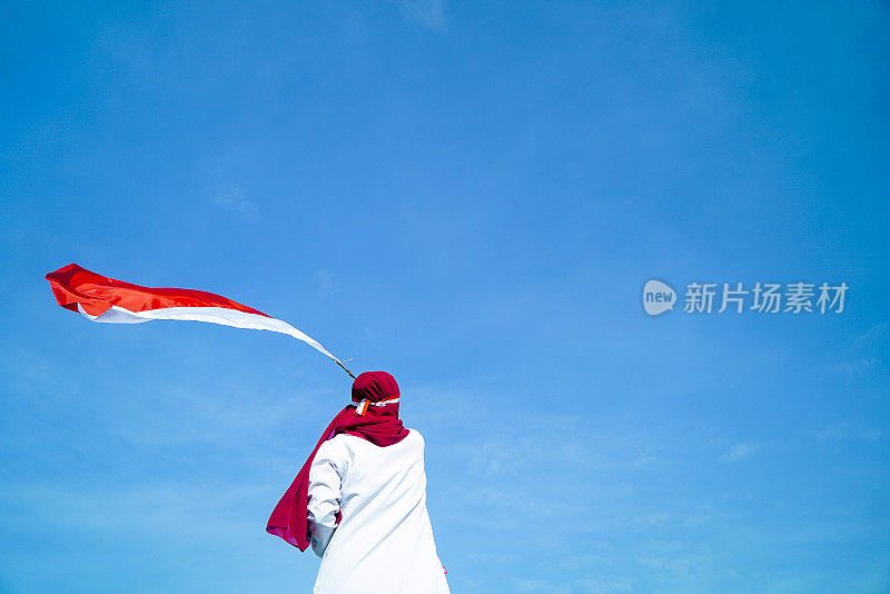 亚洲Hijab飘舞的印度尼西亚国旗与清澈的蓝天背景，印度尼西亚独立日
