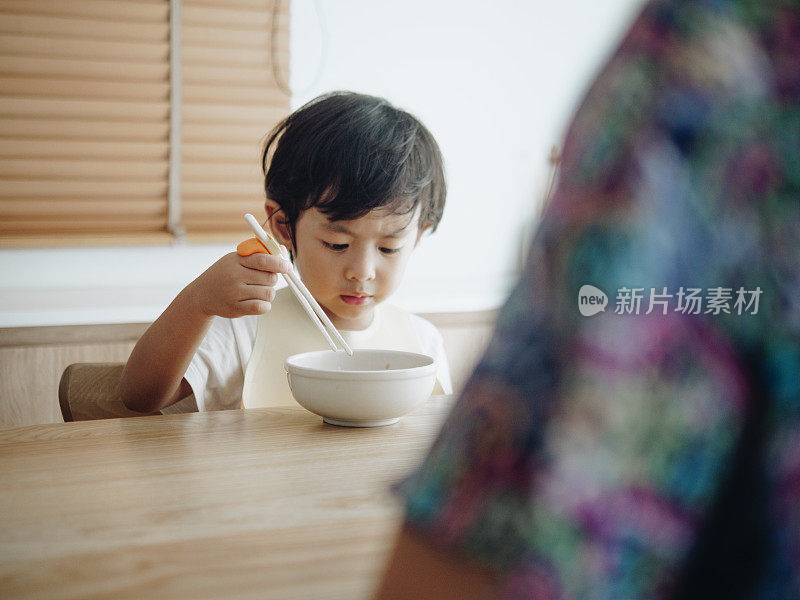 微笑的小男孩在高椅子上吃