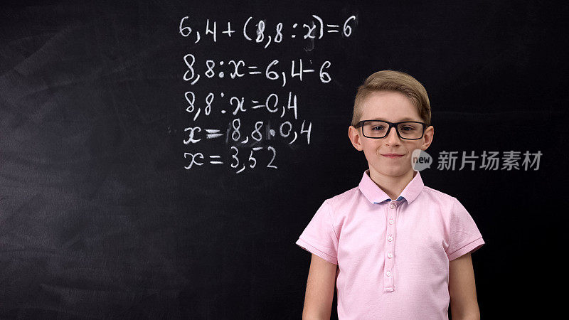 可爱的书呆子戴着眼镜站在黑板旁边做数学练习，教育