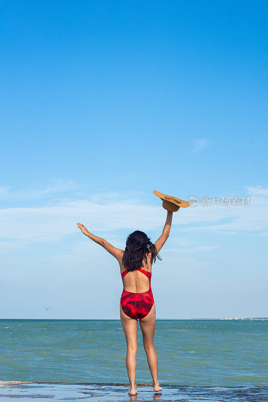 年轻快乐的女人举起双手欣赏着大海的景色